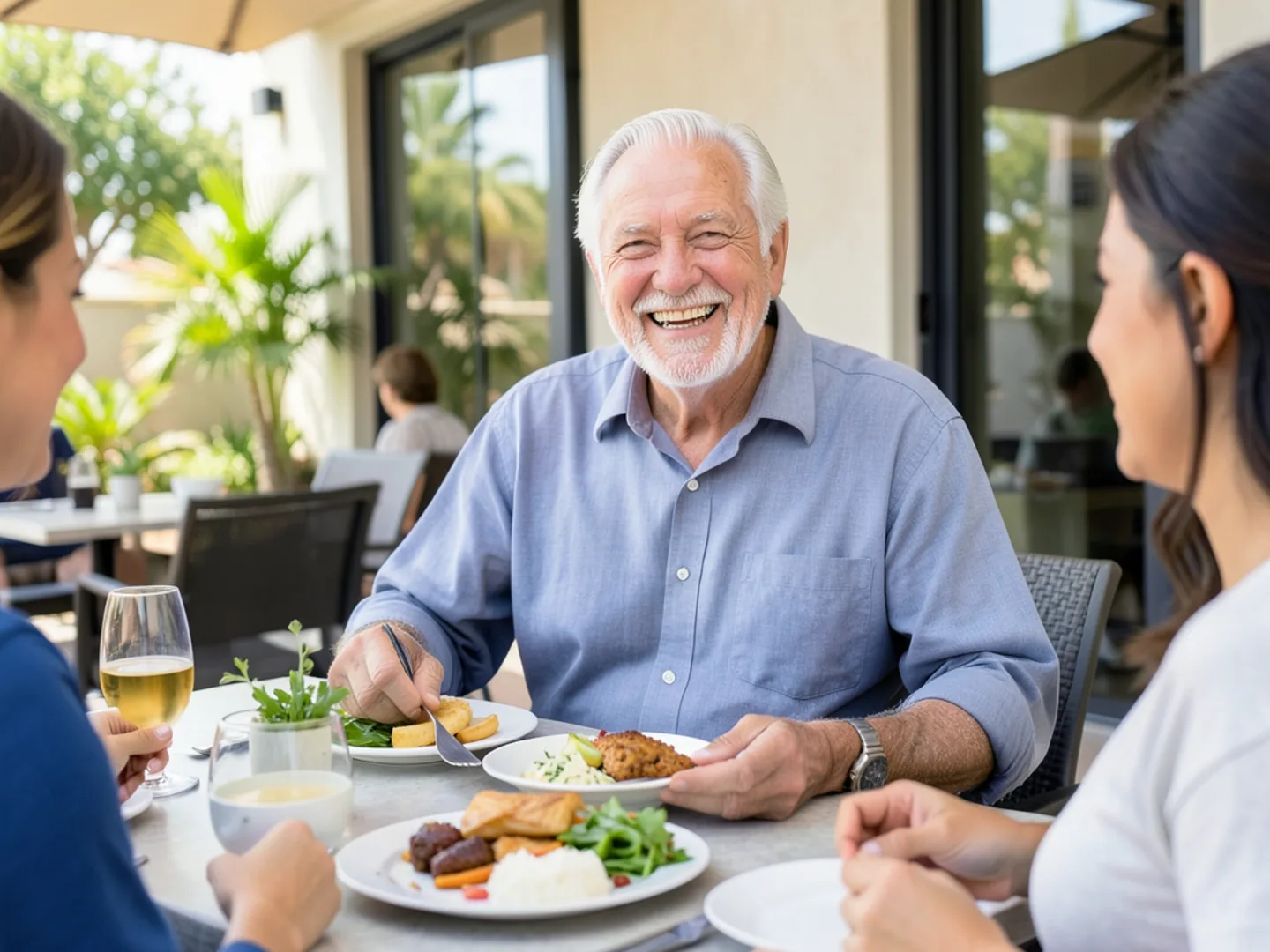 Senior man smiling broadly enjoying a family lunch outdoors with secure dentures